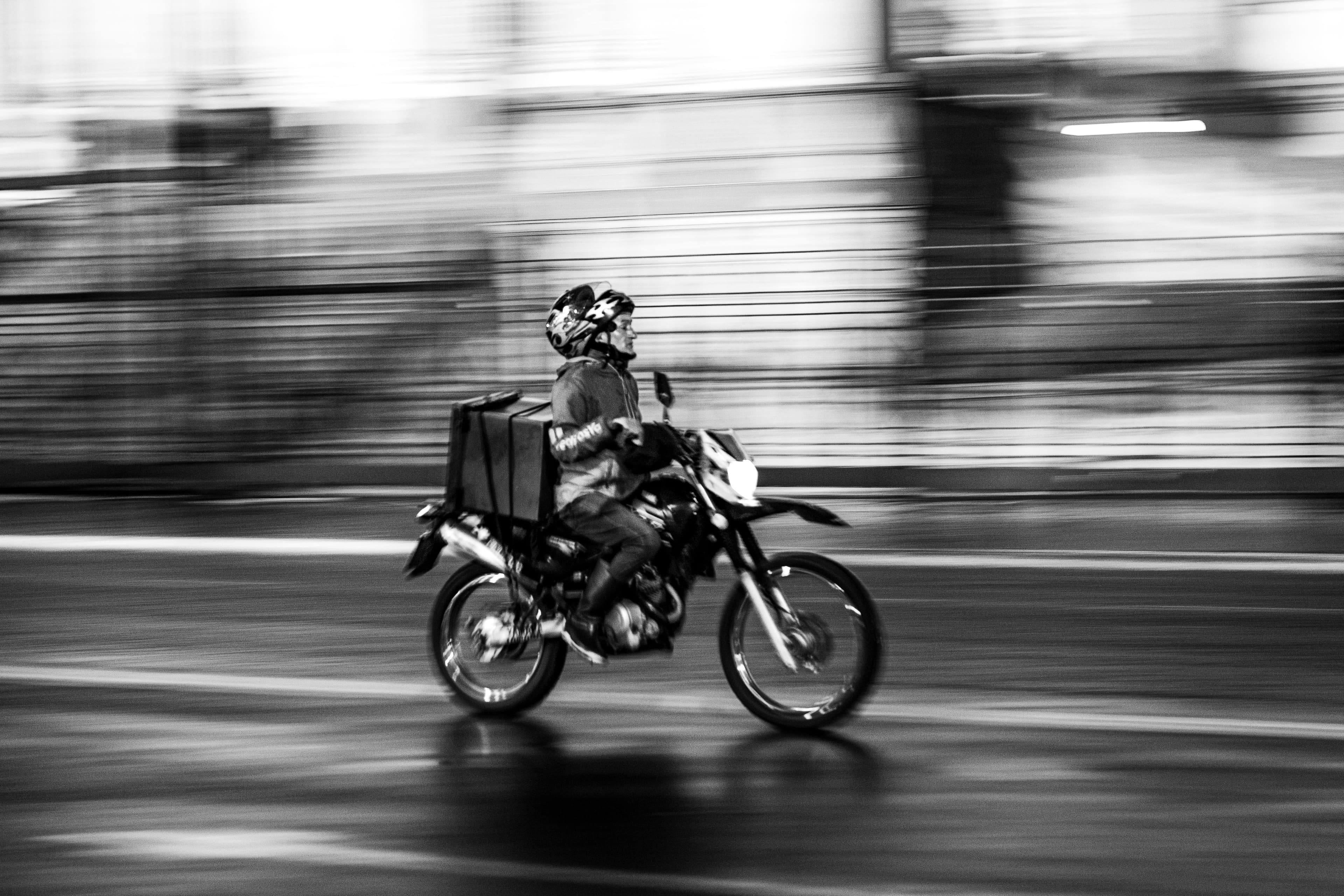 Livreur à moto en pleine course, photo noir et blanc