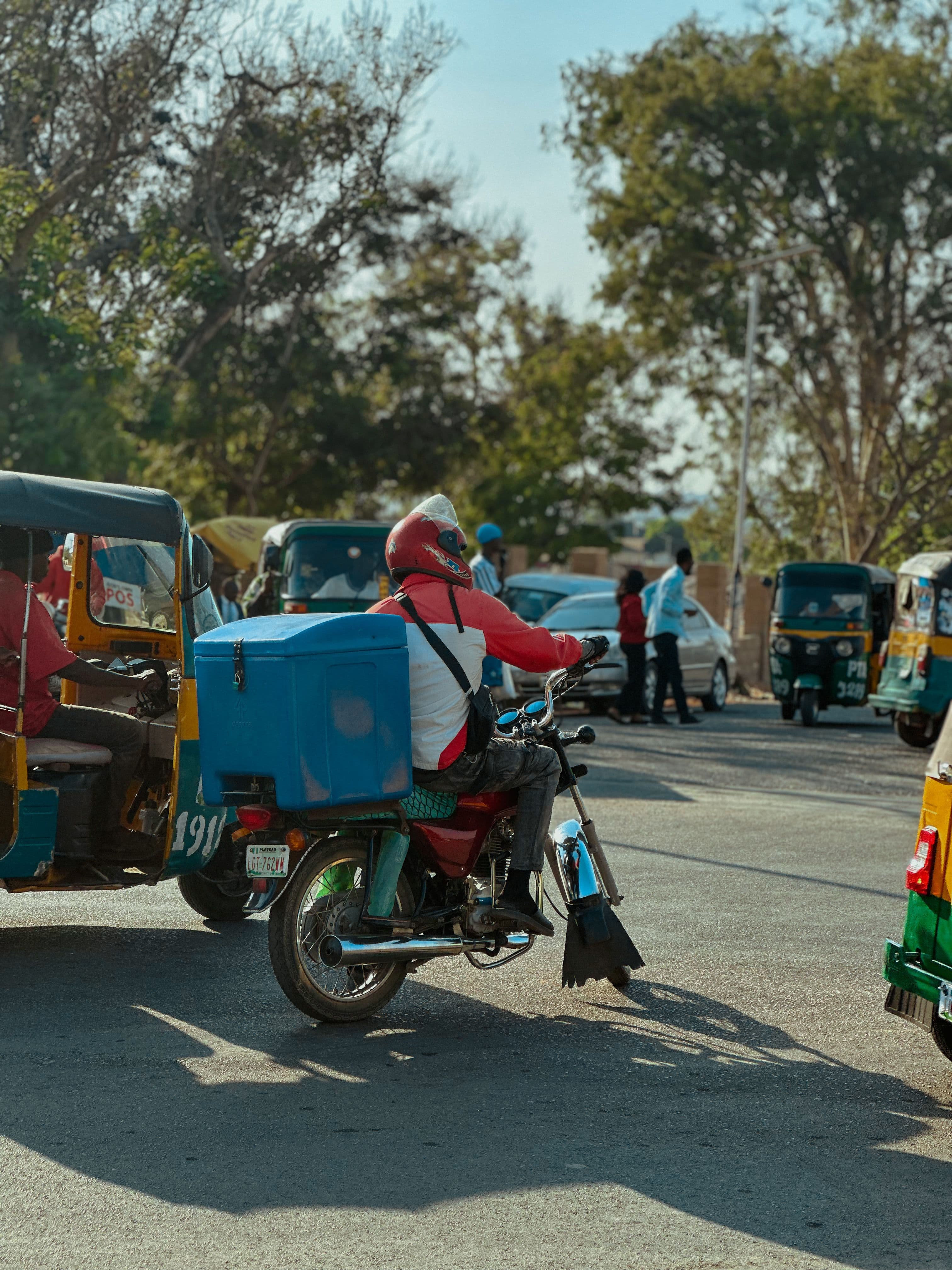 Livreur à moto avec caisse de livraison, circulation urbaine